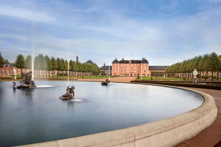 Barockschloss mit Schlossgarten und großem Brunnen im Vordergrund