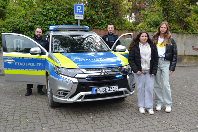 zwei Mädchen stehen vor einem Polizeiauto mit zwei Männern