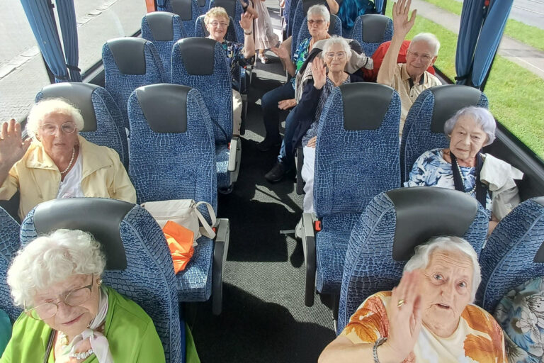 Ältere Menschen in einem Bus lächeln und winken