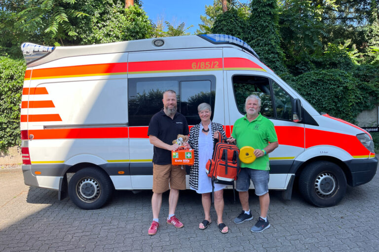 Zwei Männer und eine Frau vor einem Rettungswagen