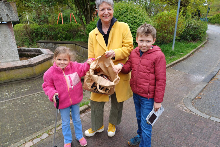 eine Frau und zwei Kinder tragen eine Papiertüte