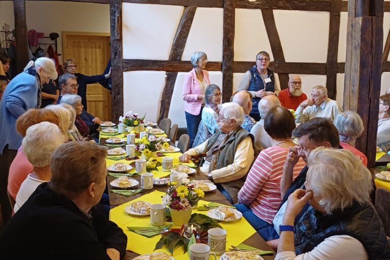 ältere Menschen sitzend an gedeckter Tafel