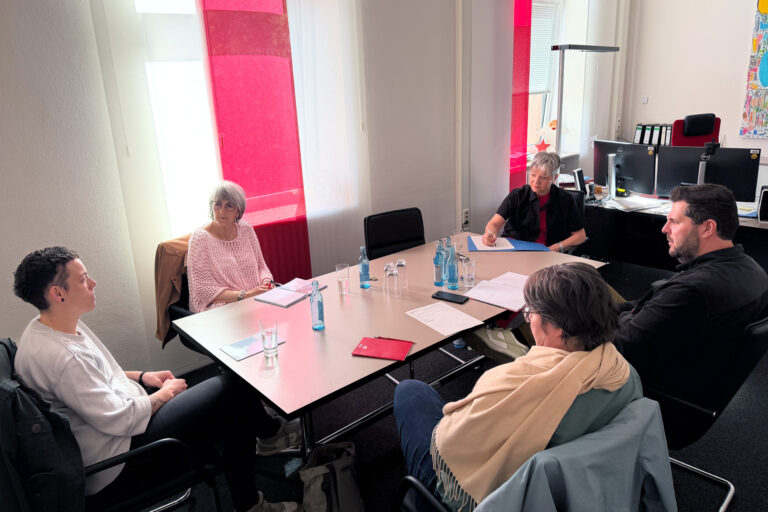Personen sitzend an einem Tisch und unterhalten sich