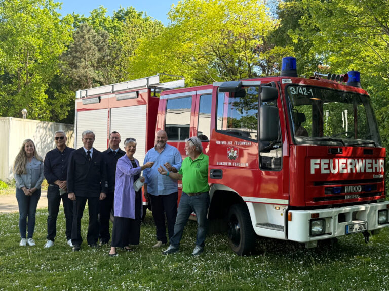 Personen stehend vor einem Feuerwehrauto