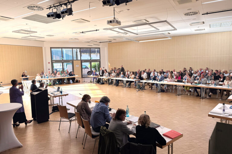 Personen sitzend und stehend in einem großen Saal