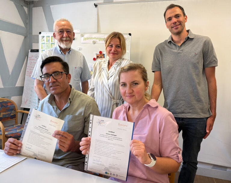 zwei Personen sitzen und drei Personen stehen dahinter