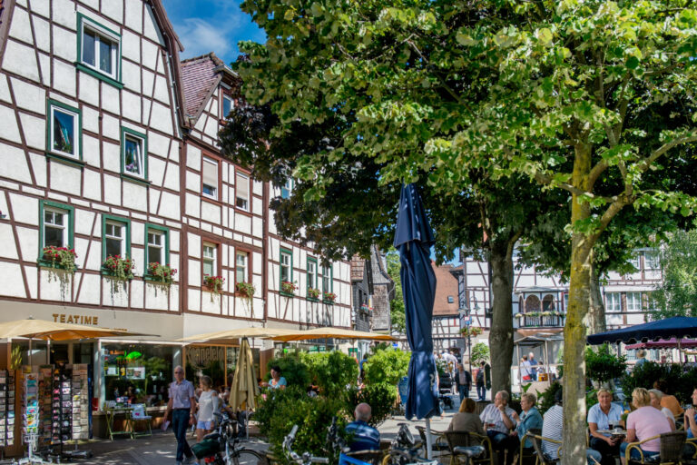 Fachwerkgebäude im Hintergrund und viele Menschen die lachen, reden und laufen