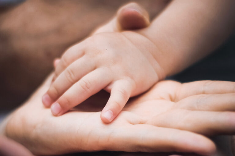 Kinderhand liegt auf Erwachsenenhand