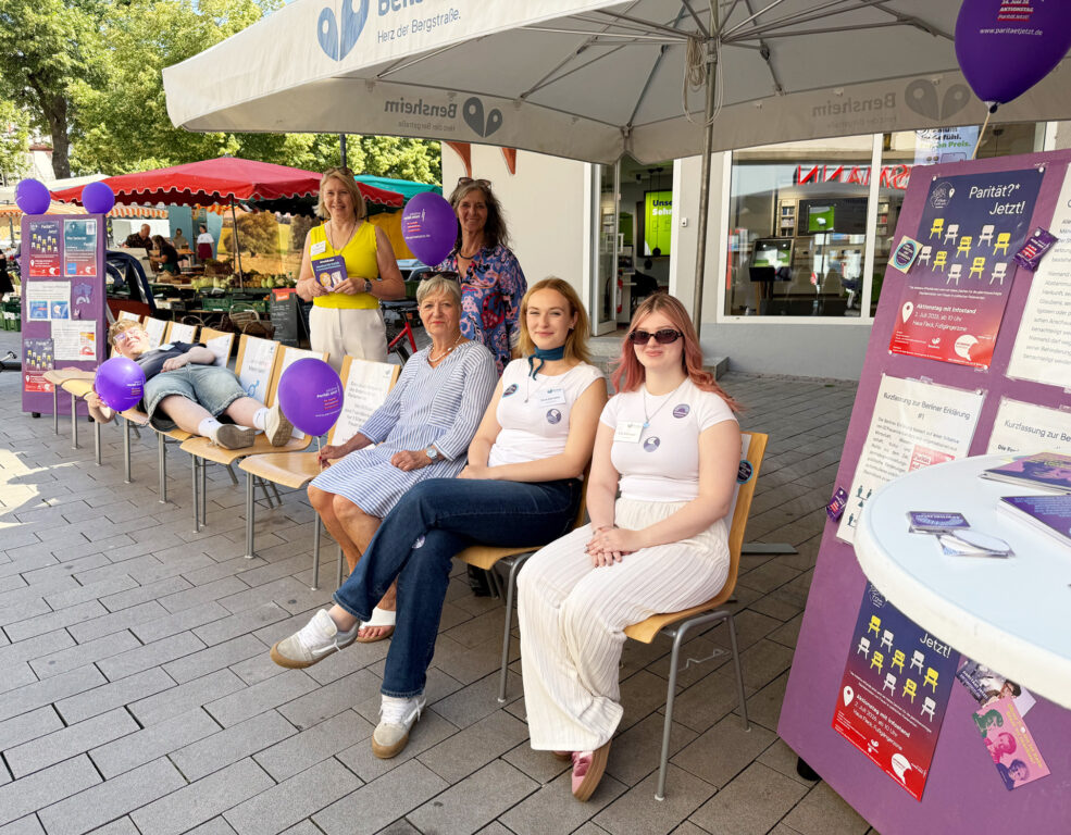 Personen sitzend und stehend und drumherum verschiedene Flyer