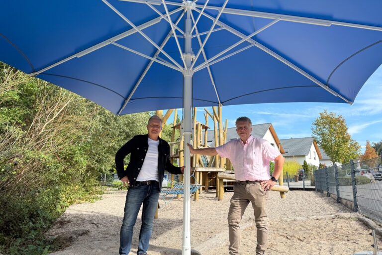 zwei Personen stehend unter einem Schirm