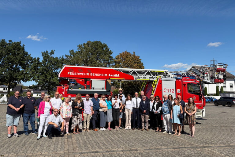 Personen stehend vor einem Feuerwehrauto