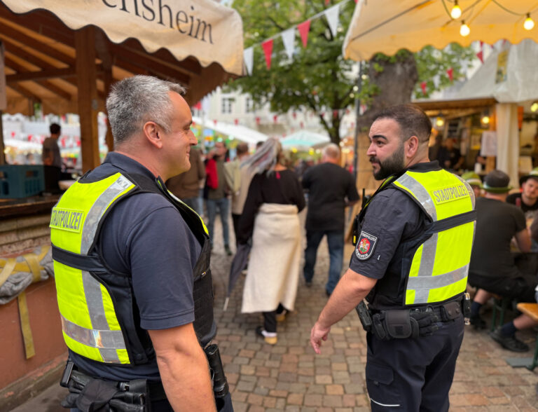 zwei Personen stehend mit gelben Westen im Winzerdorf