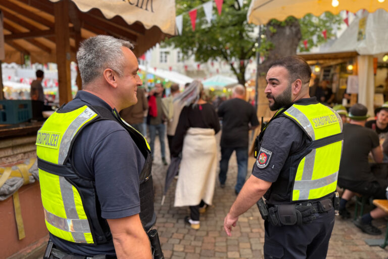 zwei Personen stehend mit gelben Westen im Winzerdorf