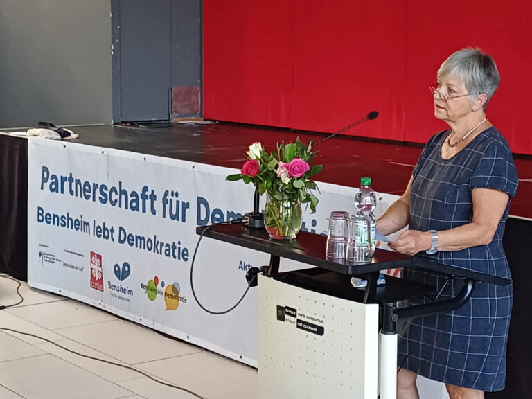 eine Person stehend an einem Pult und spricht