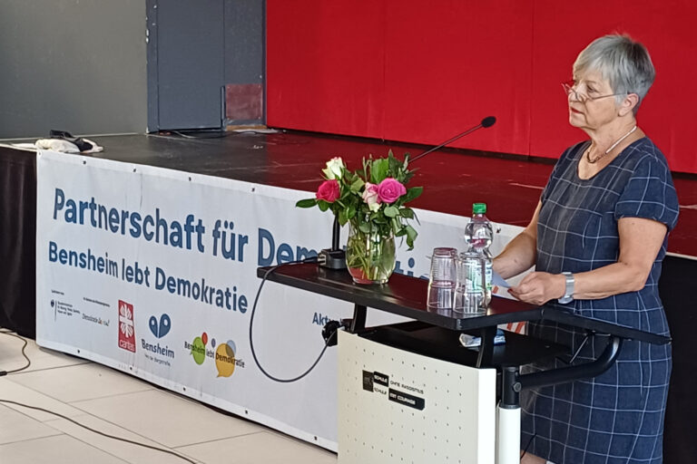 eine Person stehend an einem Pult und spricht
