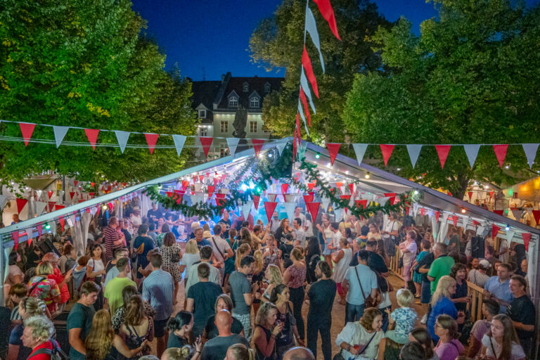 Personen tanzend in einem Zelt das bunt geschmückt ist