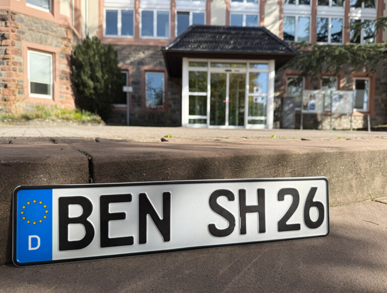 im Vordergrund das Kennzeichen mit BEN und im Hintergrund das Rathaus