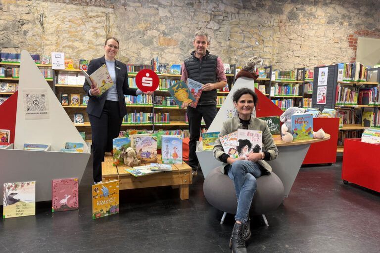 Personen sitzend und stehend vor einem Bücherregal