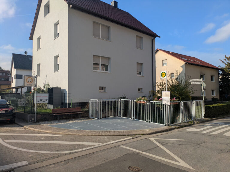 Wohngebäude und davor eine Bushaltestelle